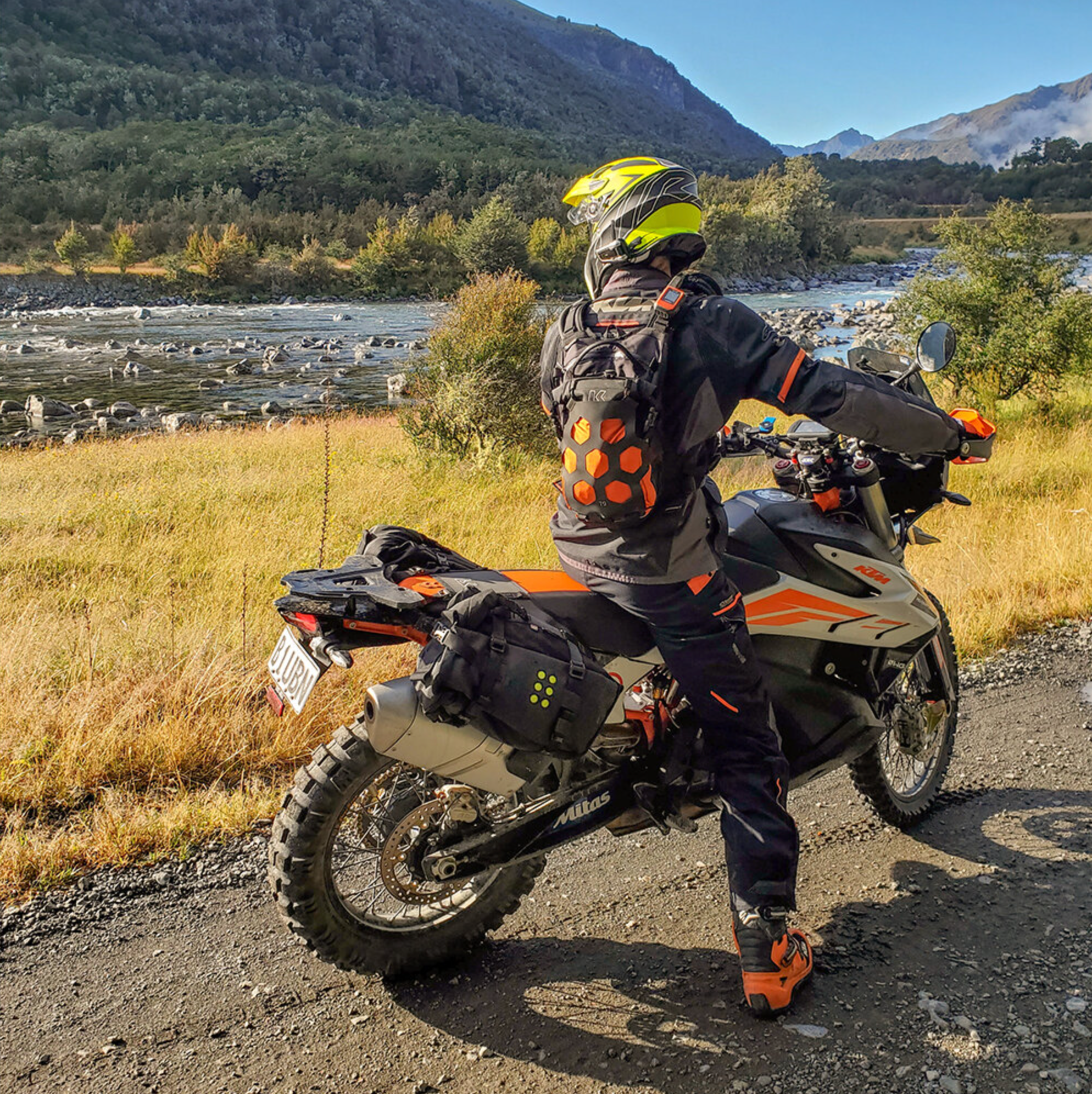 Person on a motorcycle in a scenic mountainous area with a river.