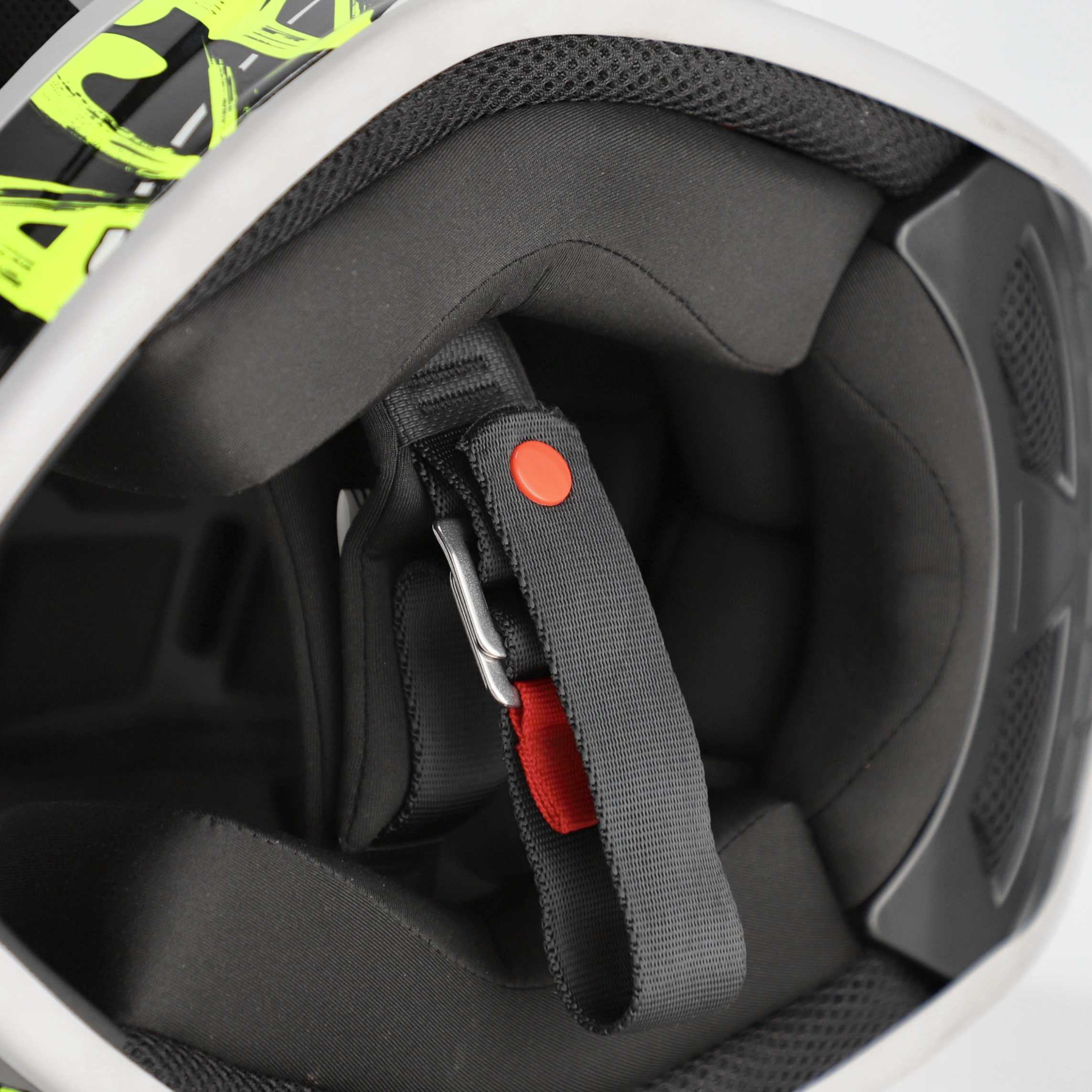 Close-up of a helmet interior with a chin strap and red buckle.