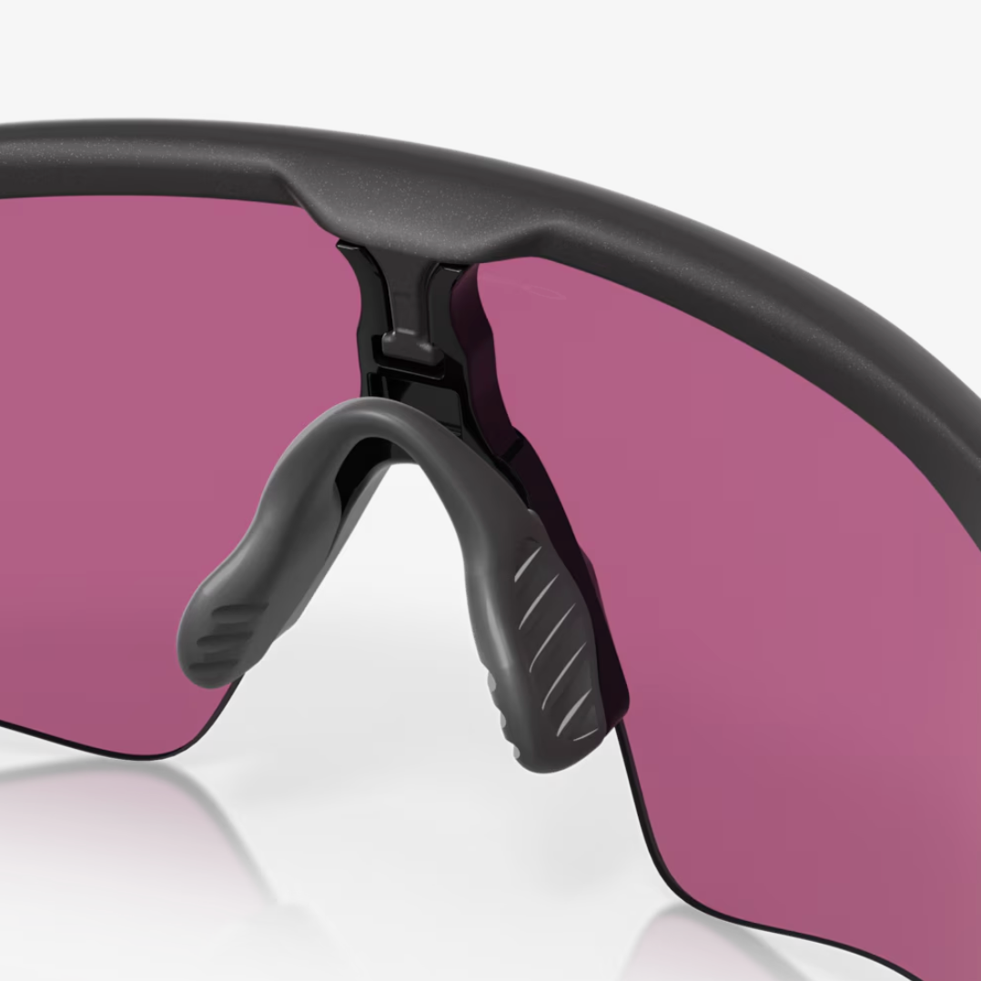 Close-up of wraparound sports sunglasses with a matte black frame and large pink-tinted lenses on a light gray background.