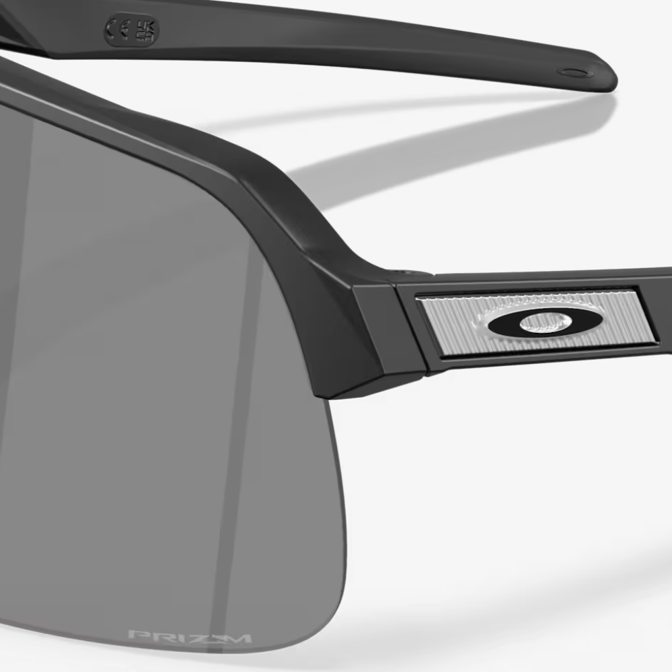 Oakley wraparound sunglasses with a matte black frame and dark gray lenses, shown at an angle on a light gray background.