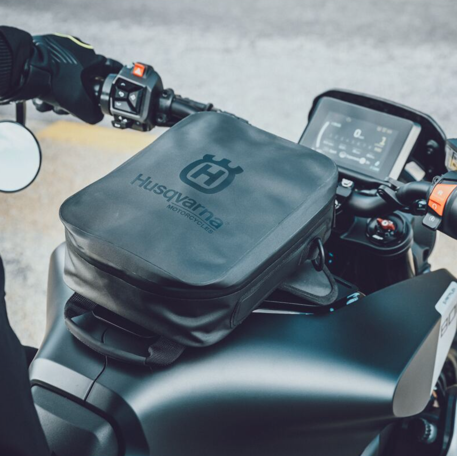 Motorcycle with a black bag featuring the Husqvarna logo on a blurred background