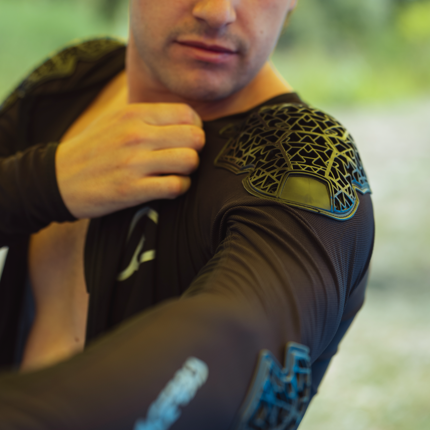 Man wearing a black athletic outfit with gold accents outdoors