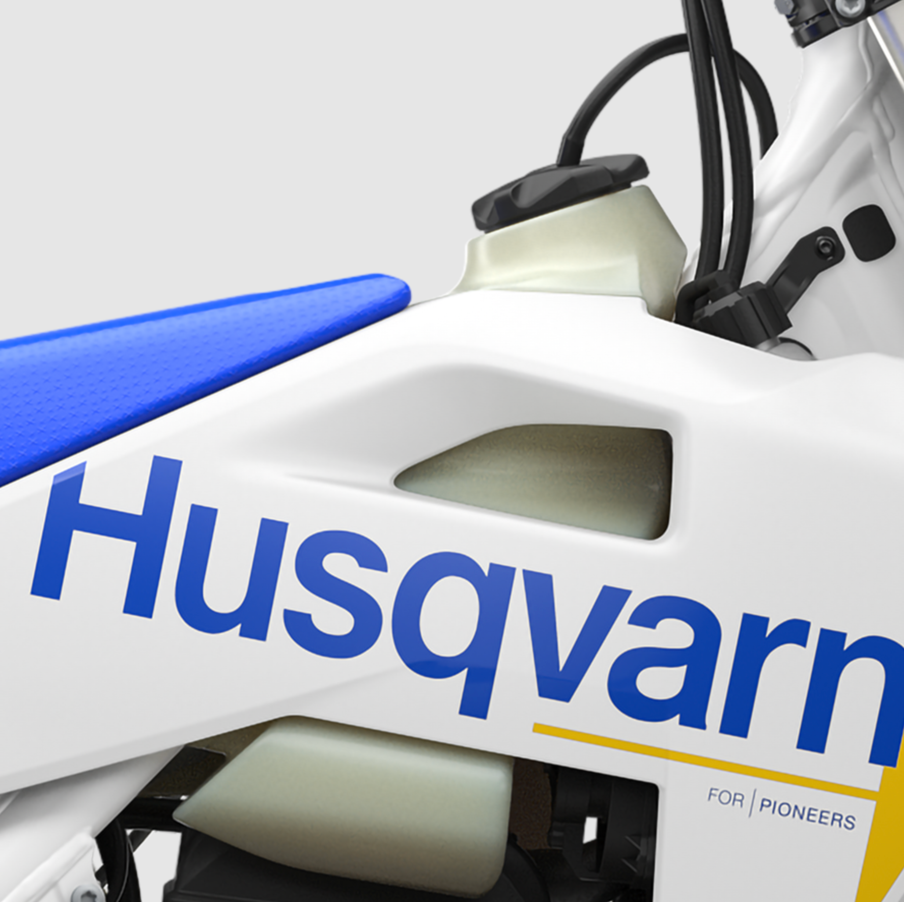 Close-up of a white Husqvarna dirt bike body panel with blue lettering, a blue seat, and black cables on a light gray background.