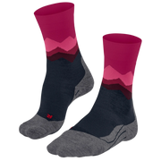 A pair of crew socks with a mountain-patterned design in magenta, pink, and dark red, featuring a navy blue midfoot and a heather gray toe and heel, shown on a plain white background.