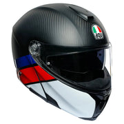 A close-up studio shot of an AGV full-face motorcycle helmet. The helmet features a black and dark gray carbon fiber pattern on the top, a clear visor, a white lower section, and a blue and red stripe detail on the side.