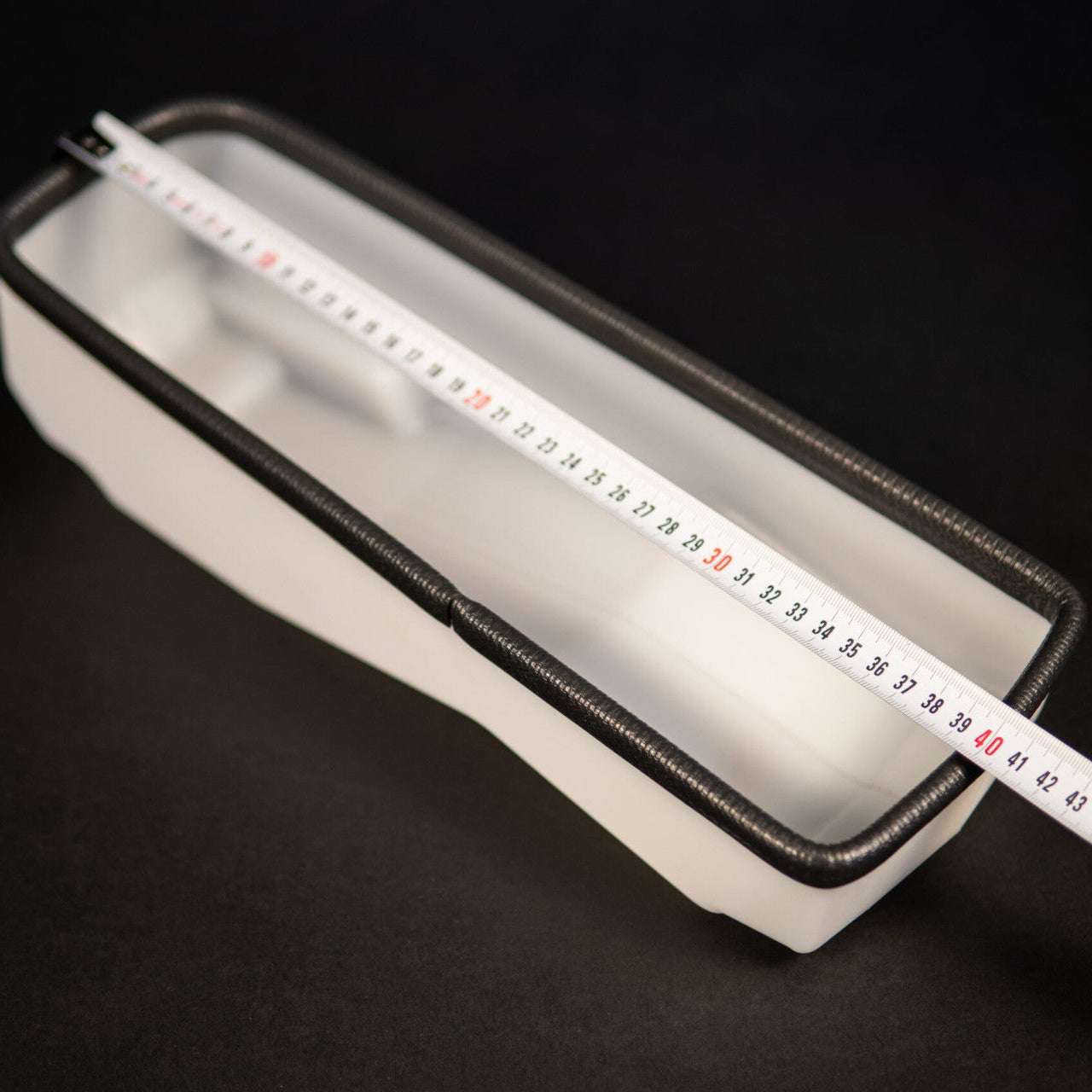 Rectangular white container with a ruler on a black background